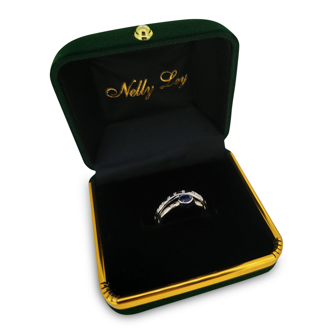 Gold ring with a blue gemstone in a green and gold jewelry box labeled 'Nelly Lea'.