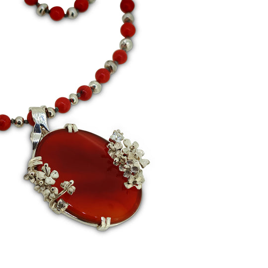Necklace with red pendant and silver accents on a white background