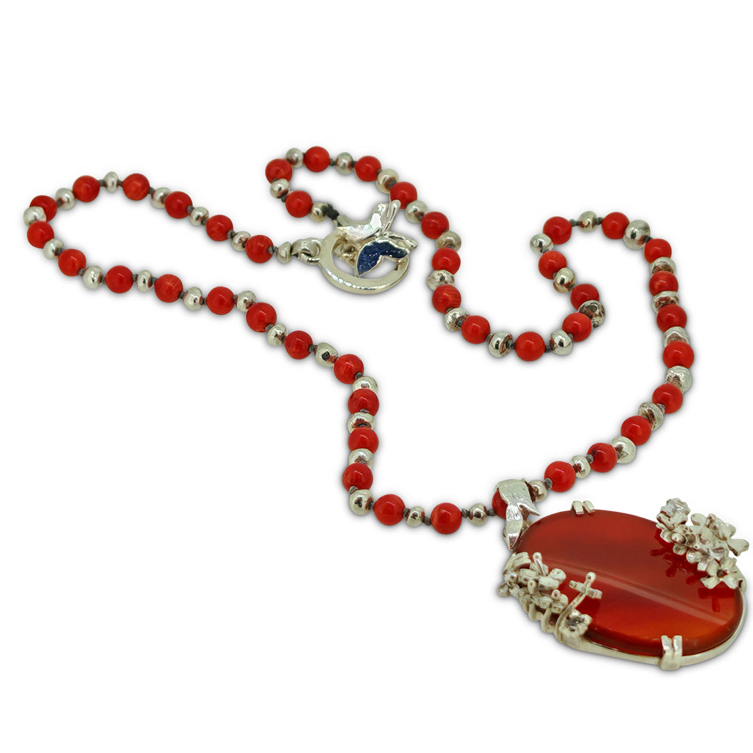 Necklace with red beads and a large red heart pendant on a white background