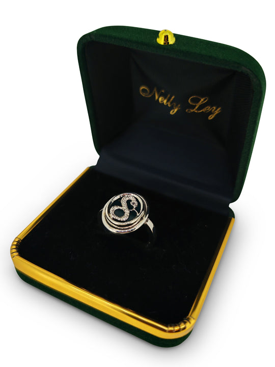 Silver ring with a black stone in a green and gold jewelry box on a white background