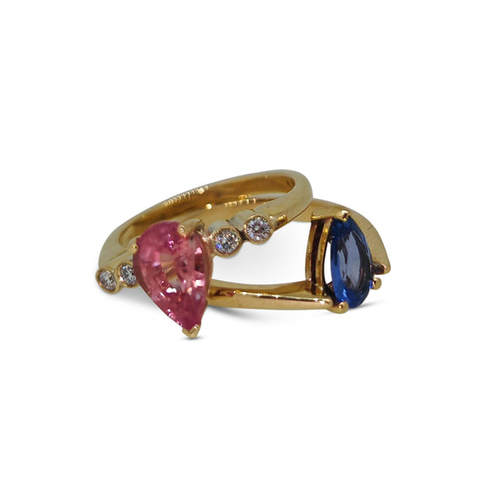 Gold ring with pink and blue gemstones on a white background